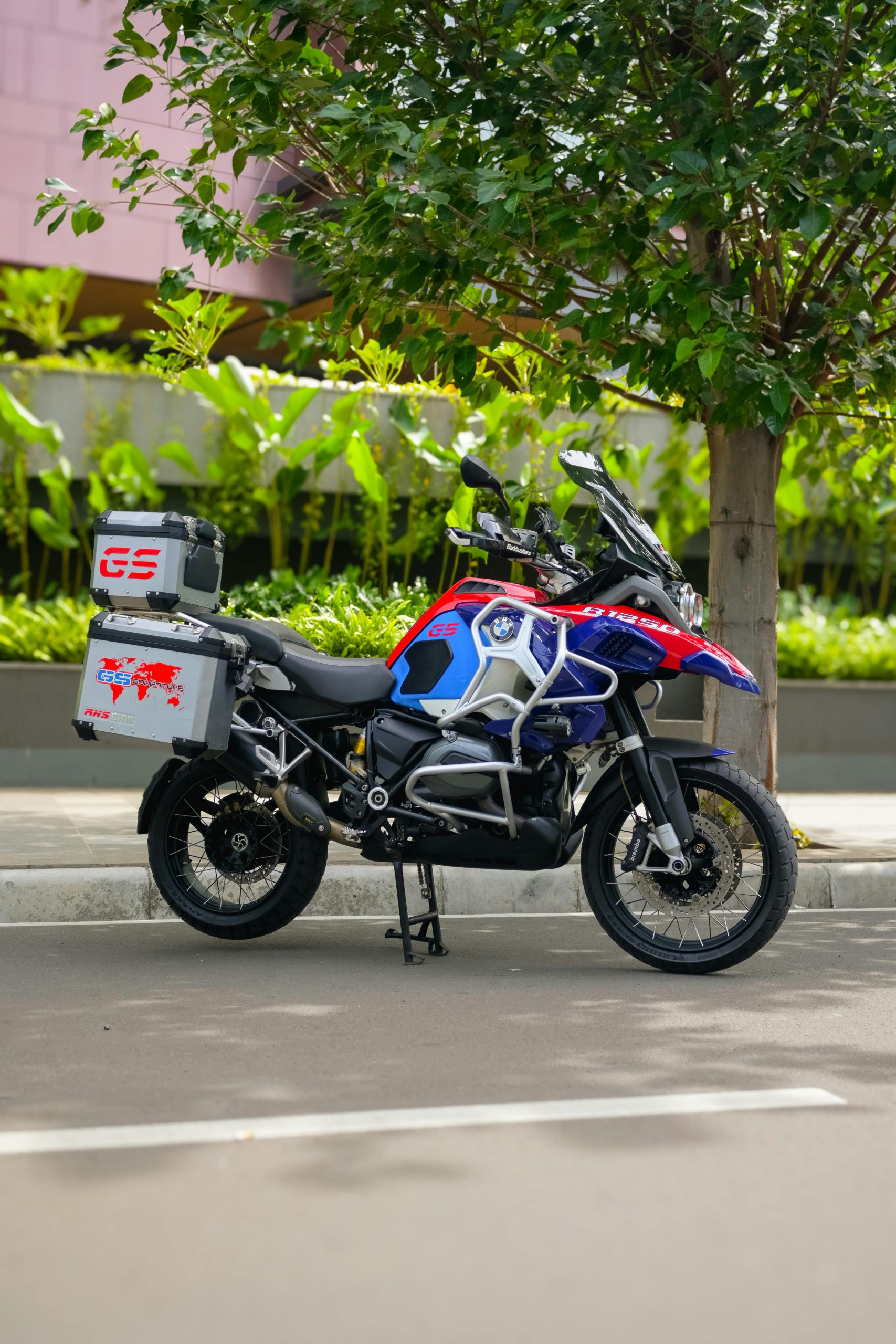Aventureuse moto vibrante garée sous un arbre dans une rue ensoleillée, illustrant l'exploration urbaine.