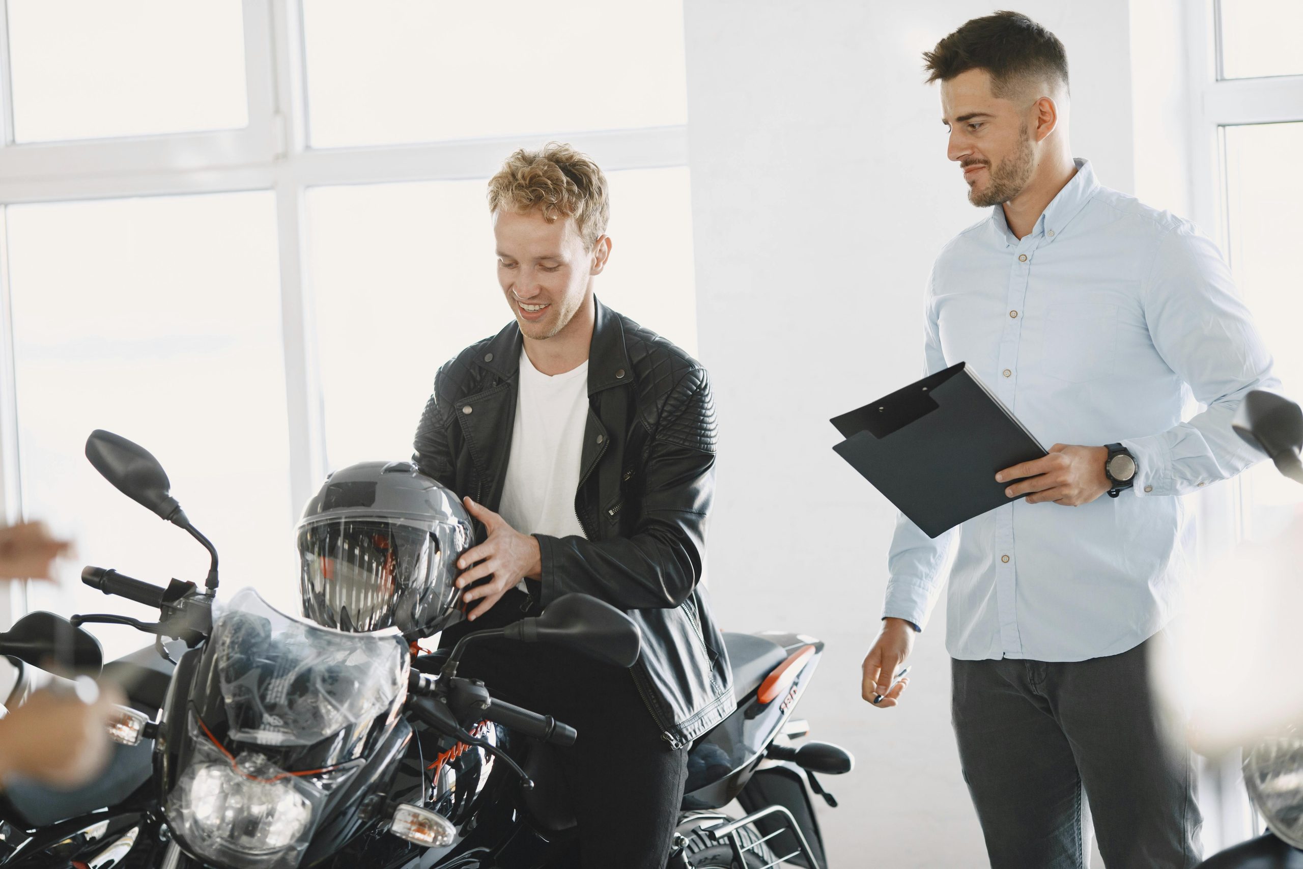 Two men at a motorcycle dealership discussing a motorbike purchase. Deux hommes dans un magasin de motos discutant d'un achat de moto.