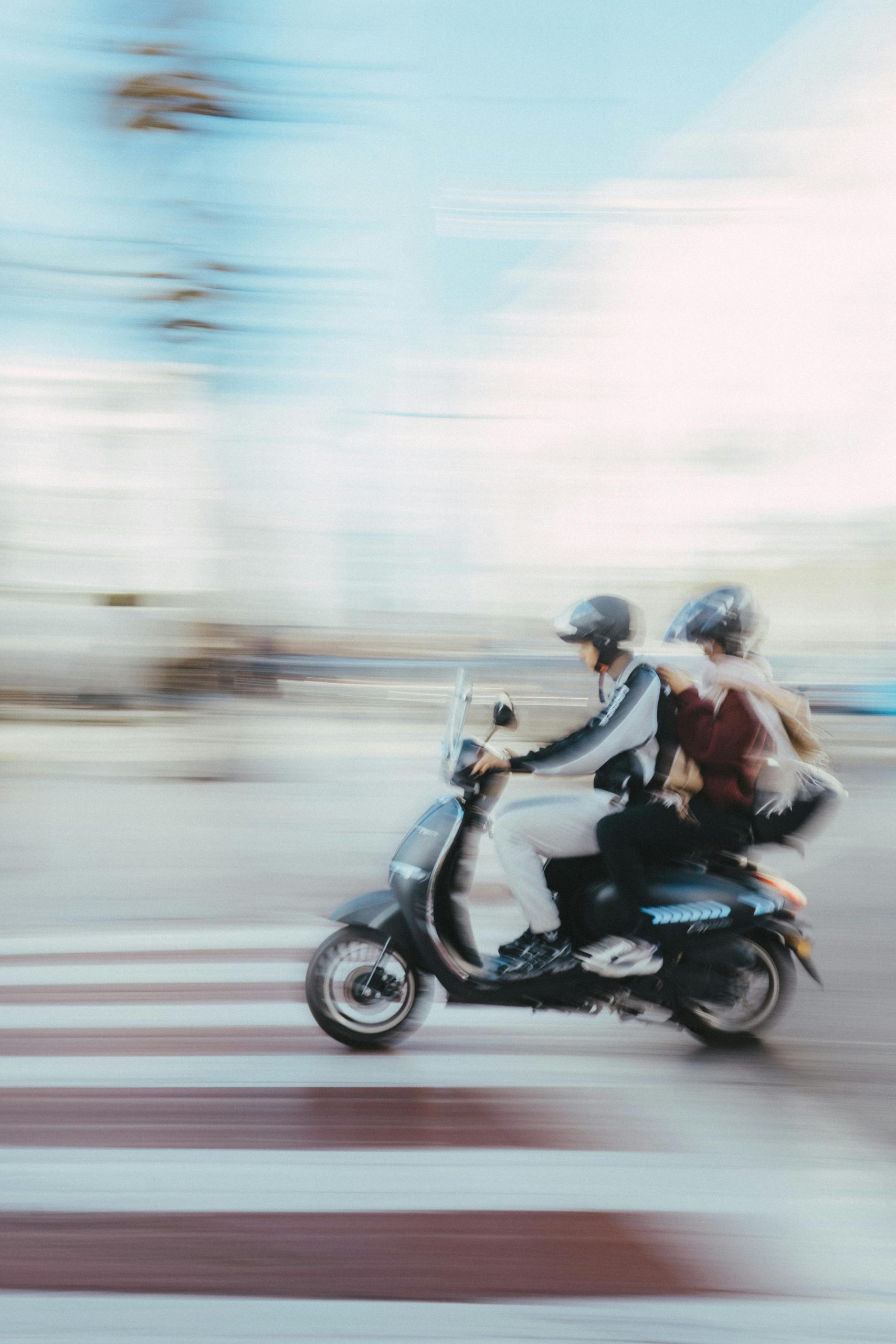Two motorcyclists navigate a winding road lined with poles and barriers. Deux motards empruntent une route sinueuse bordée de poteaux et de barrières.