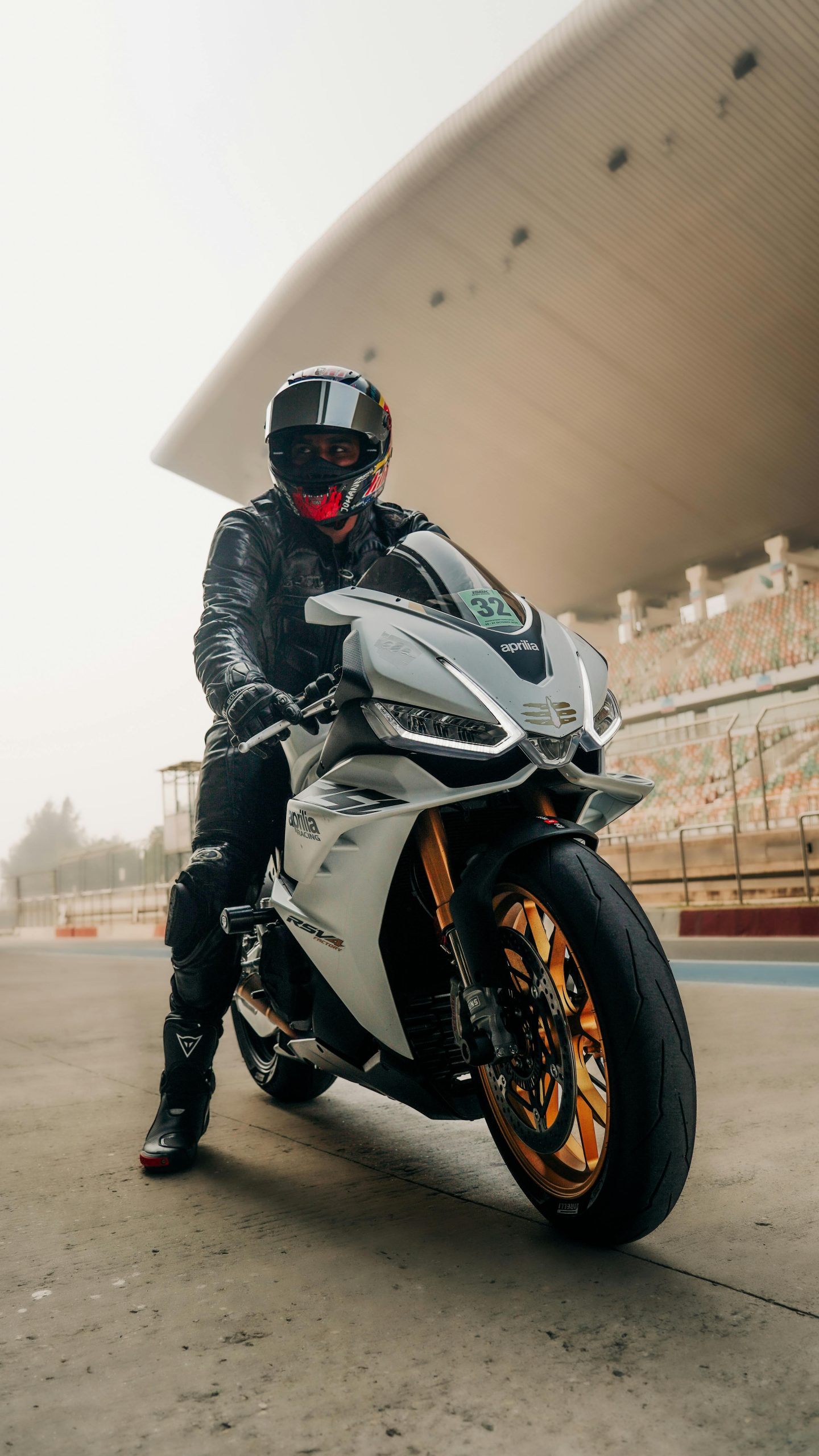 Cavalier en casque et combinaison en cuir sur une moto sportive sur un circuit de course, mettant en avant la vitesse et le style.