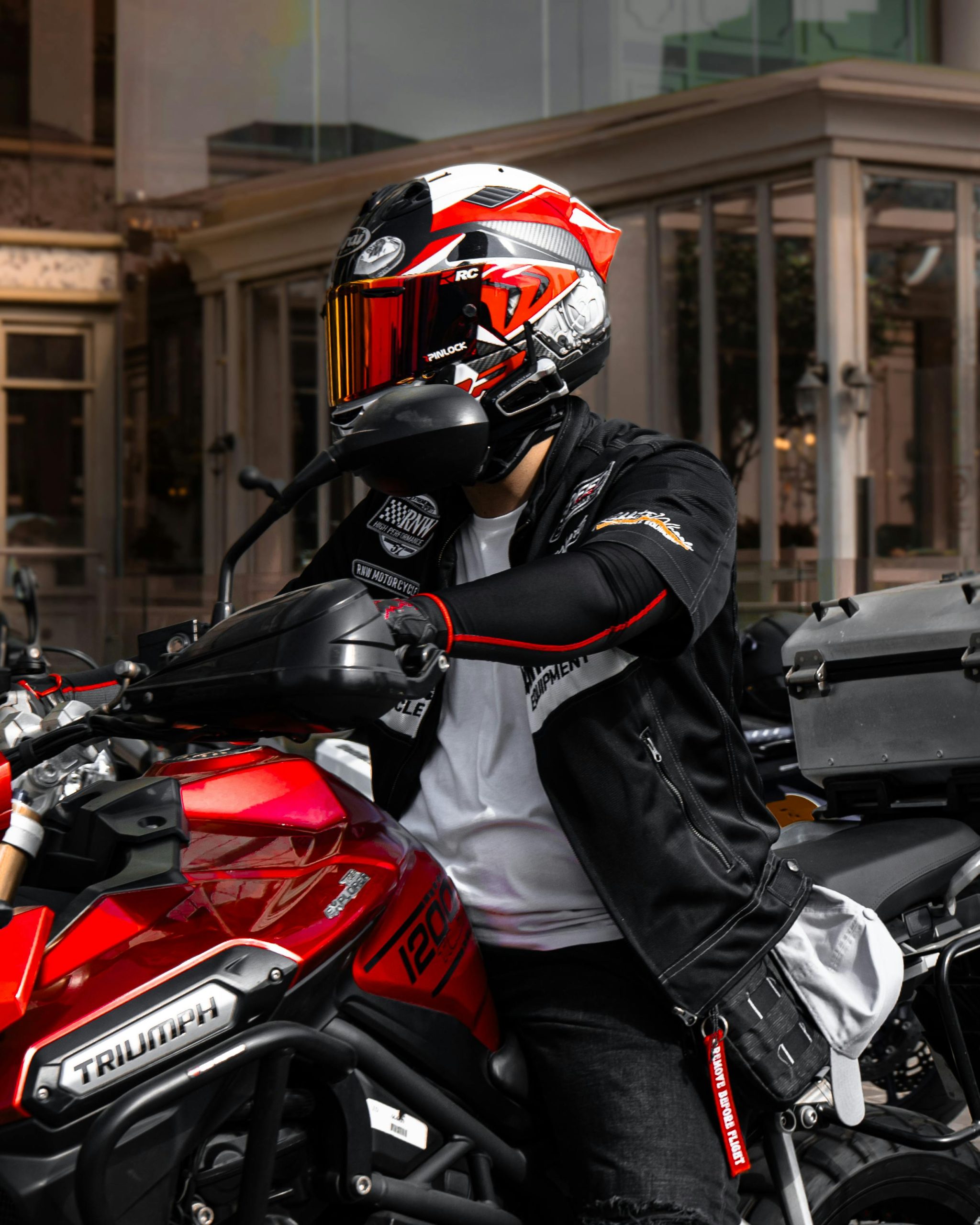 Urbaniste en équipement de moto sur une Triumph 1200 rouge. Tenue de sécurité stylée pour l'aventure.