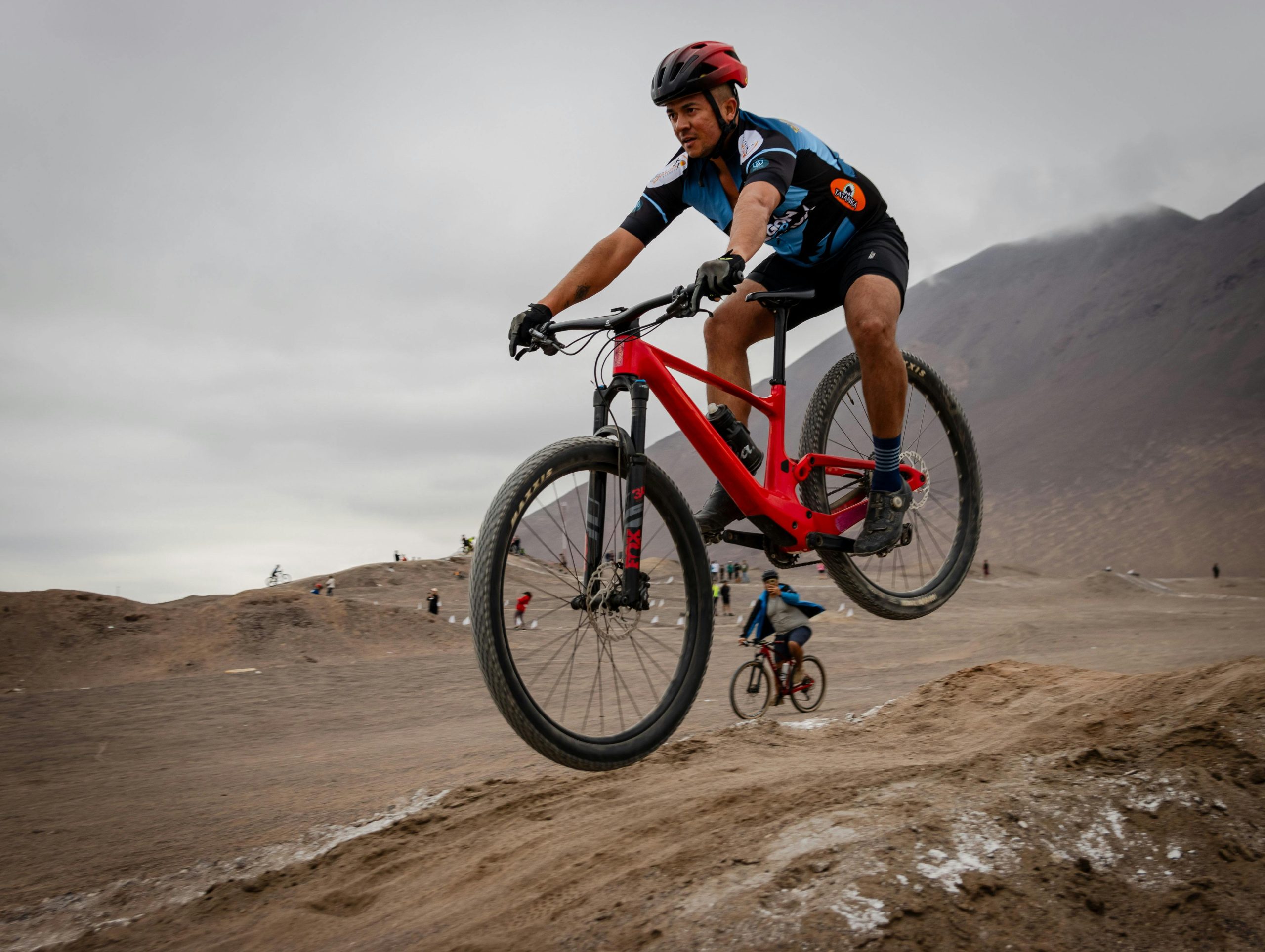 Mountain biker effectuant un saut sur une piste tout-terrain accidentée lors d'une course.