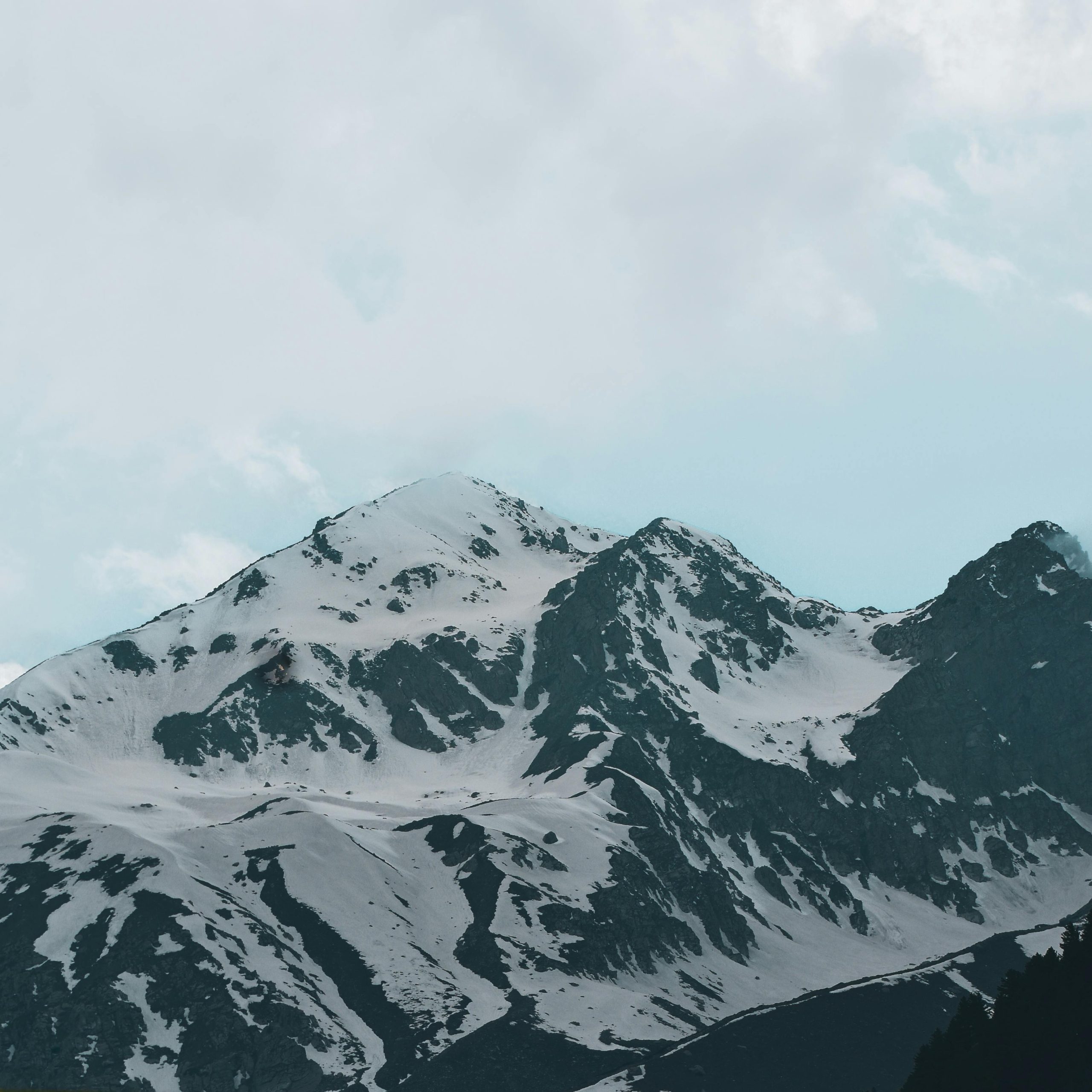 Breathtaking snow-covered mountain range sous un ciel nuageux, mettant en valeur la beauté de la nature.