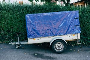 Une bâche bleue recouvrant une remorque garée sur le bord d'une route près d'une haie, idéale pour les thèmes de transport.