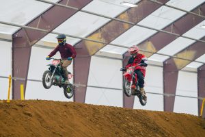 Two riders compete in a thrilling indoor dirt bike race in Martinsburg, Ohio. Deux cavaliers se font concurrence dans une palpitante course de dirt bike en intérieur à Martinsburg, Ohio.