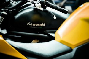 Close-up of a Kawasaki Vulcan S motorcycle's tank and handlebar with raindrops, highlighting its sleek design. Gros plan sur le réservoir et le guidon d'une motocyclette Kawasaki Vulcan S avec des gouttes de pluie, mettant en évidence son design élégant.