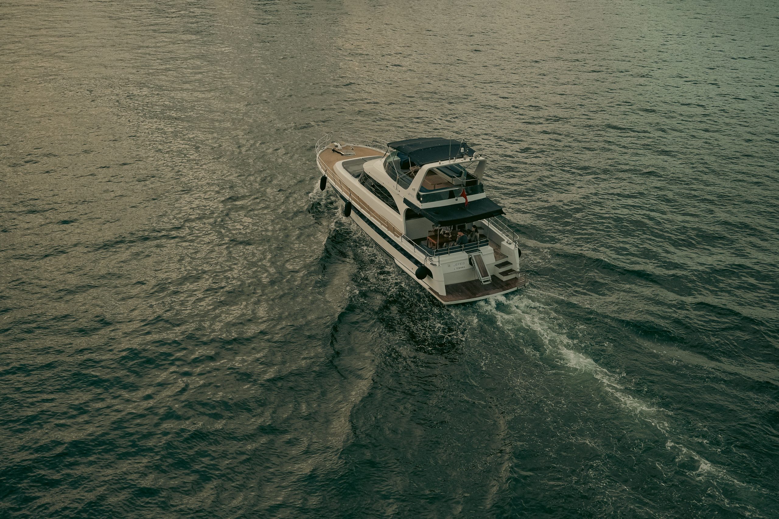 A drone shot capturing a luxury yacht sailing smoothly across the serene and vast sea surface. Une vue de drone capturant un yacht de luxe naviguant en douceur sur la surface de la mer sereine et vaste.