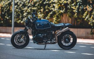 Élégante moto noire garée dans une rue urbaine sous la lumière du soleil, mettant en avant son design moderne.