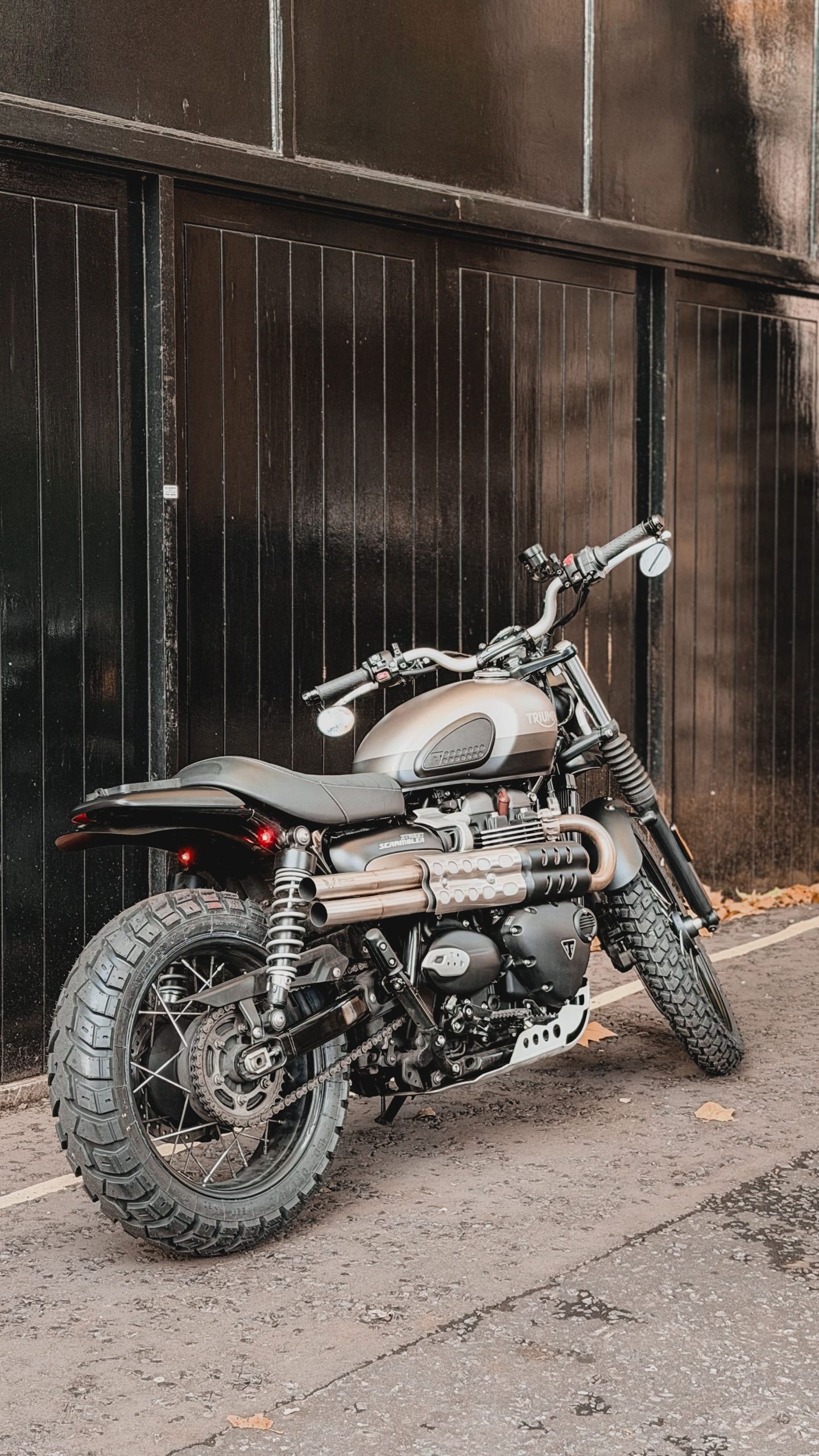 Stylish black Triumph scrambler motorbike parked outdoors on urban street. Un élégant motocyclette Triumph scrambler noire garée à l'extérieur dans une rue urbaine.