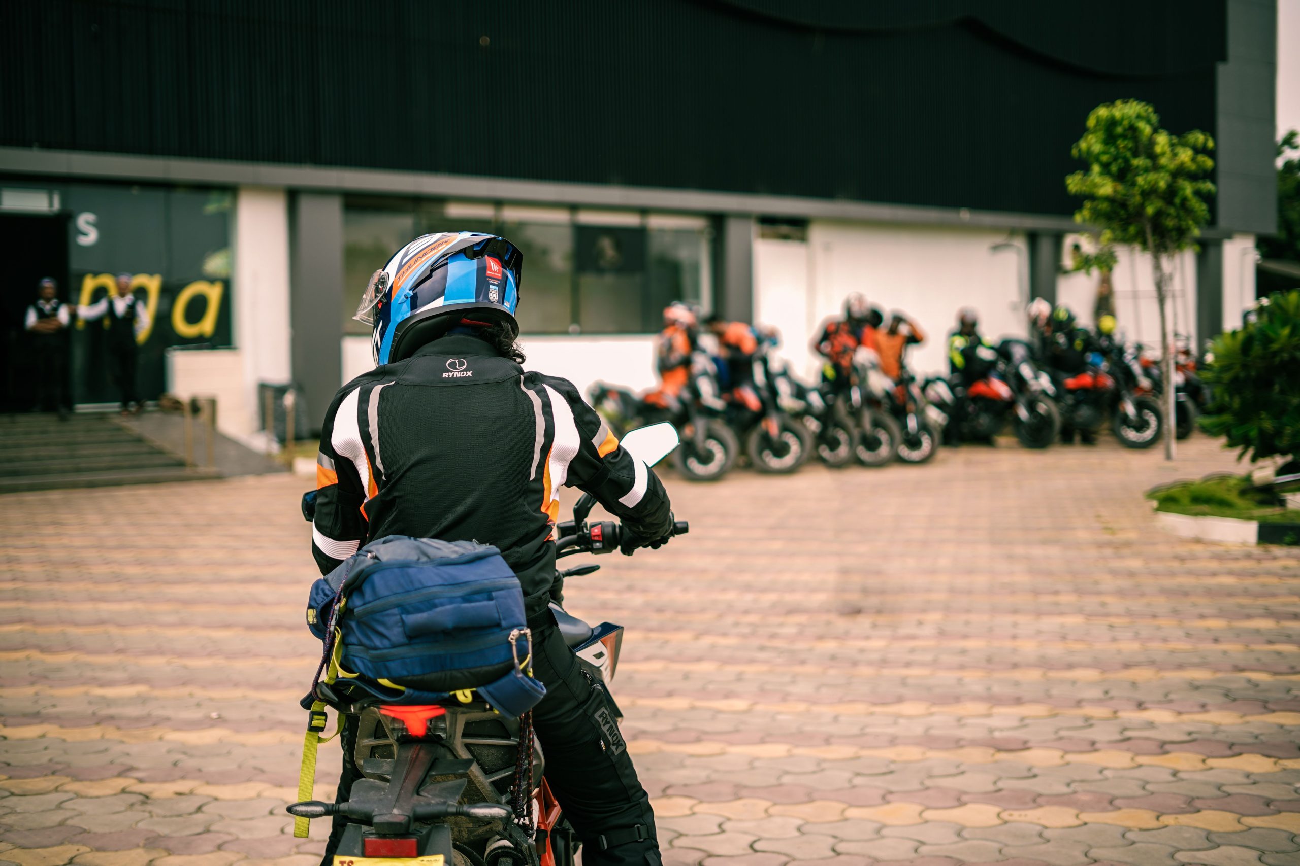 Motorcyclist in gear heads towards a group ready for a touring adventure. Un motocycliste équipé se dirige vers un groupe prêt pour une aventure de tourisme à moto.