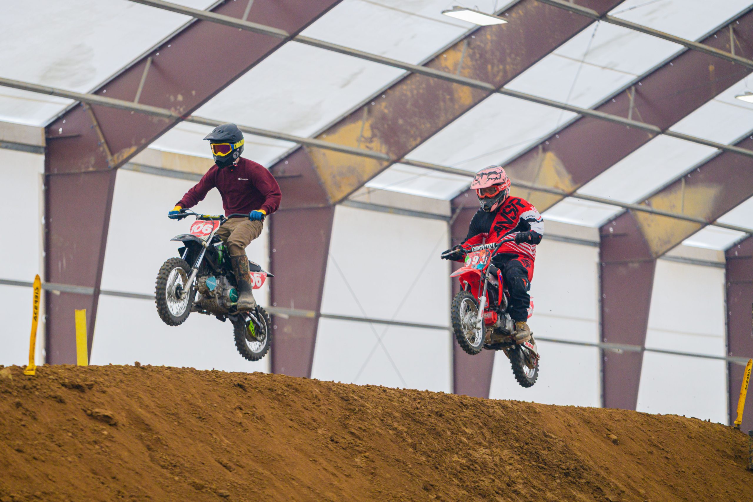 Two riders compete in a thrilling indoor dirt bike race in Martinsburg, Ohio. Deux cavaliers participent à une passionnante course de motocross en intérieur à Martinsburg, Ohio.