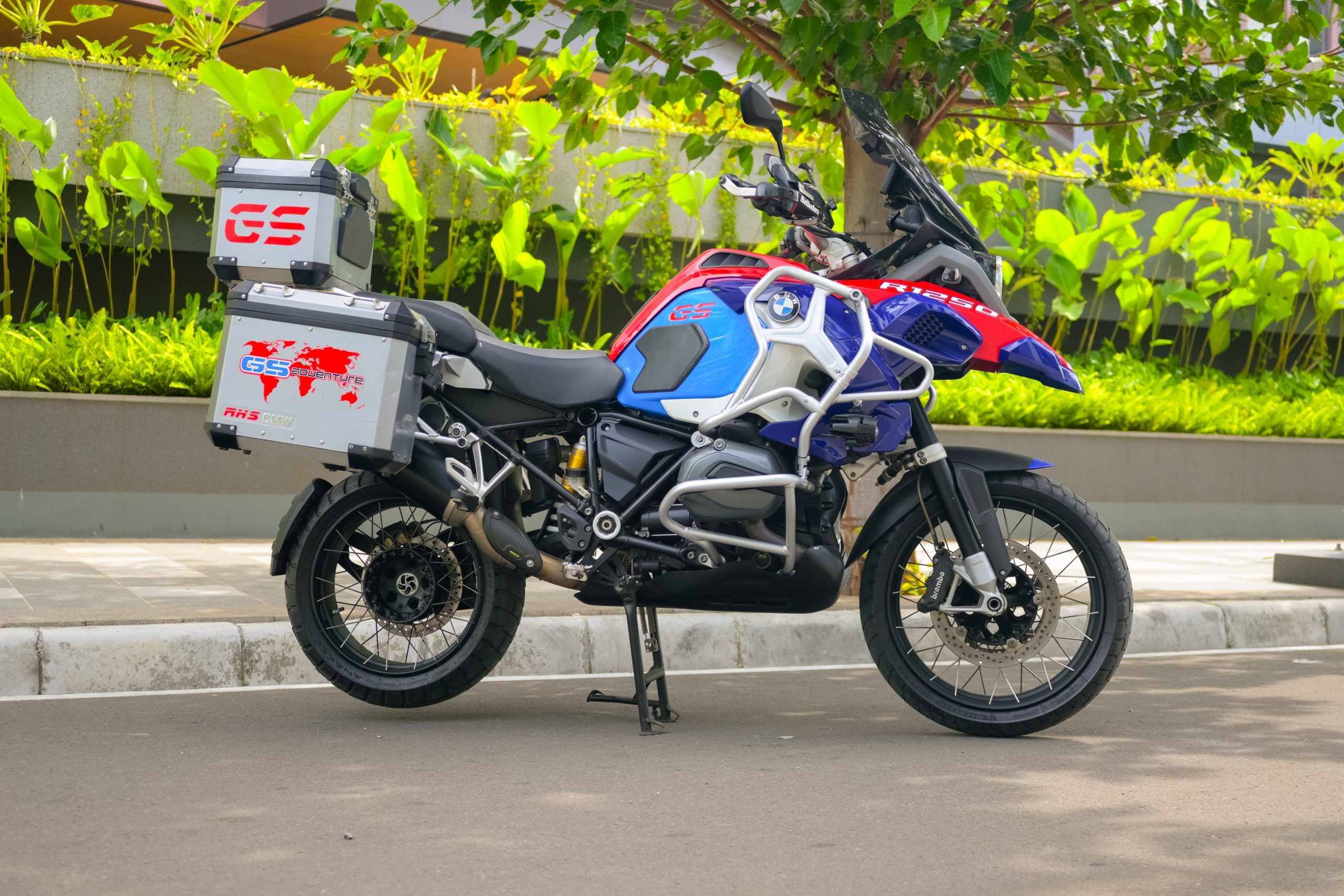 A brightly colored motorcycle parked on a street in Indonesia with lush greenery in the background. Une moto aux couleurs vives garée dans une rue en Indonésie avec une végétation luxuriante en arrière-plan.