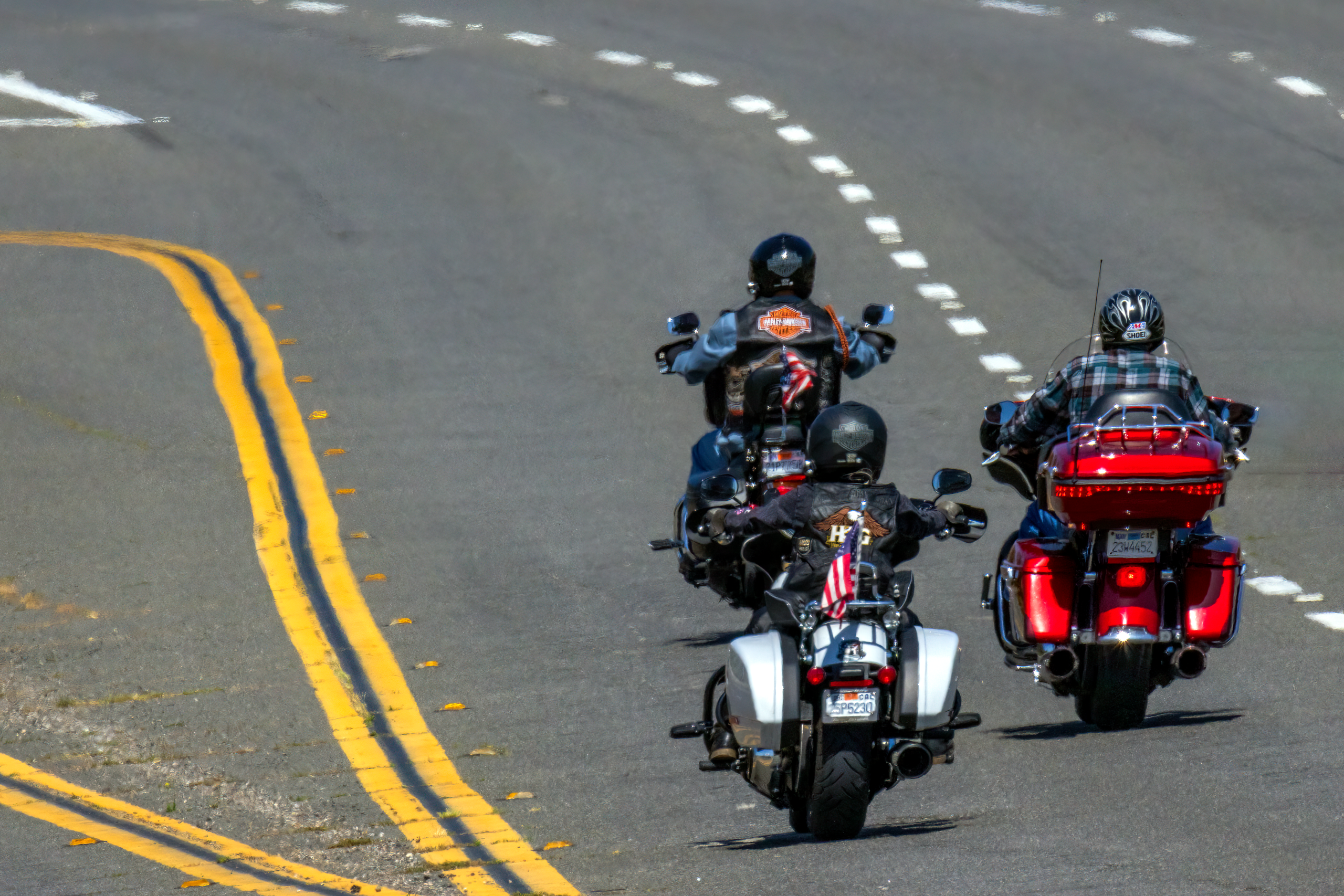 Three motorcyclists riding freely on a highway, enjoying the thrill of the open road. Trois motocyclistes roulant librement sur une autoroute, savourant l'adrénaline de la route ouverte.