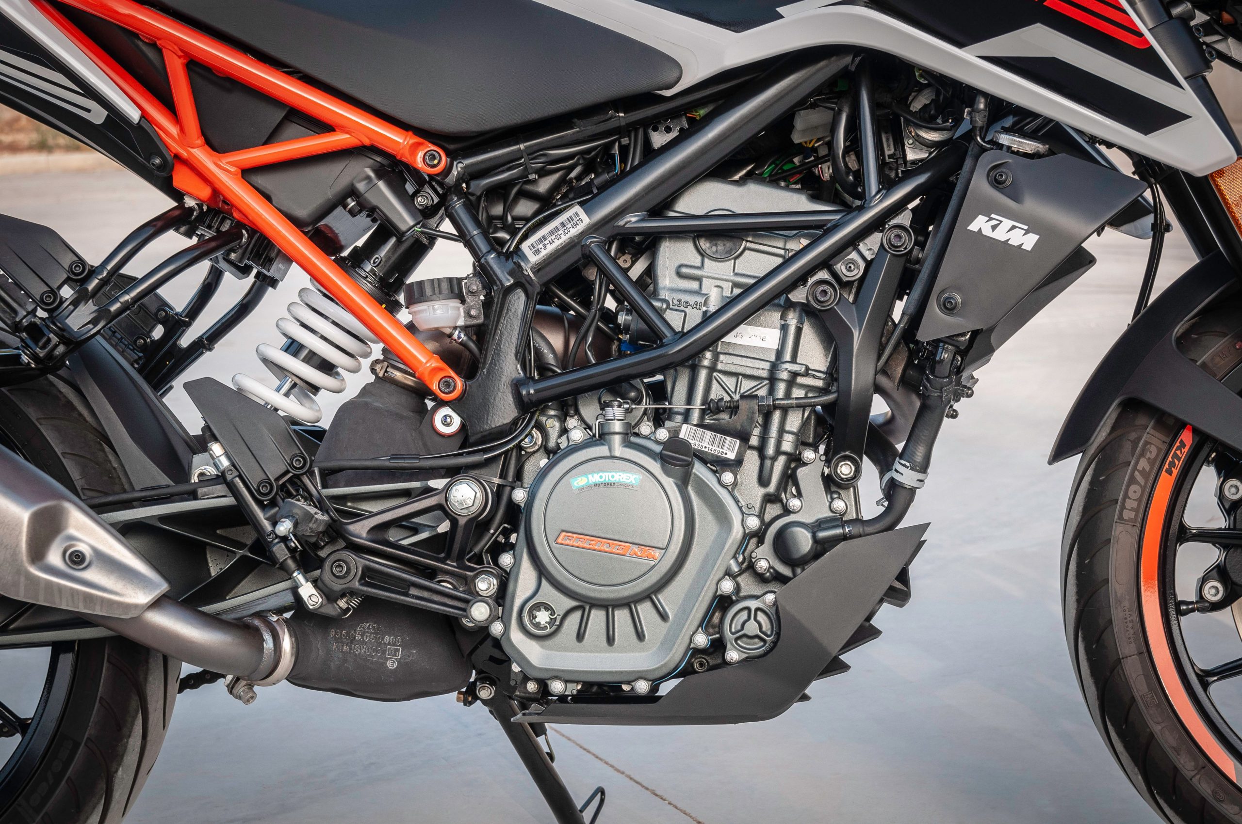 Detailed view of a KTM motorcycle engine showcasing design and machinery outdoors. Vue détaillée du moteur d'une moto KTM montrant le design et la mécanique en extérieur.