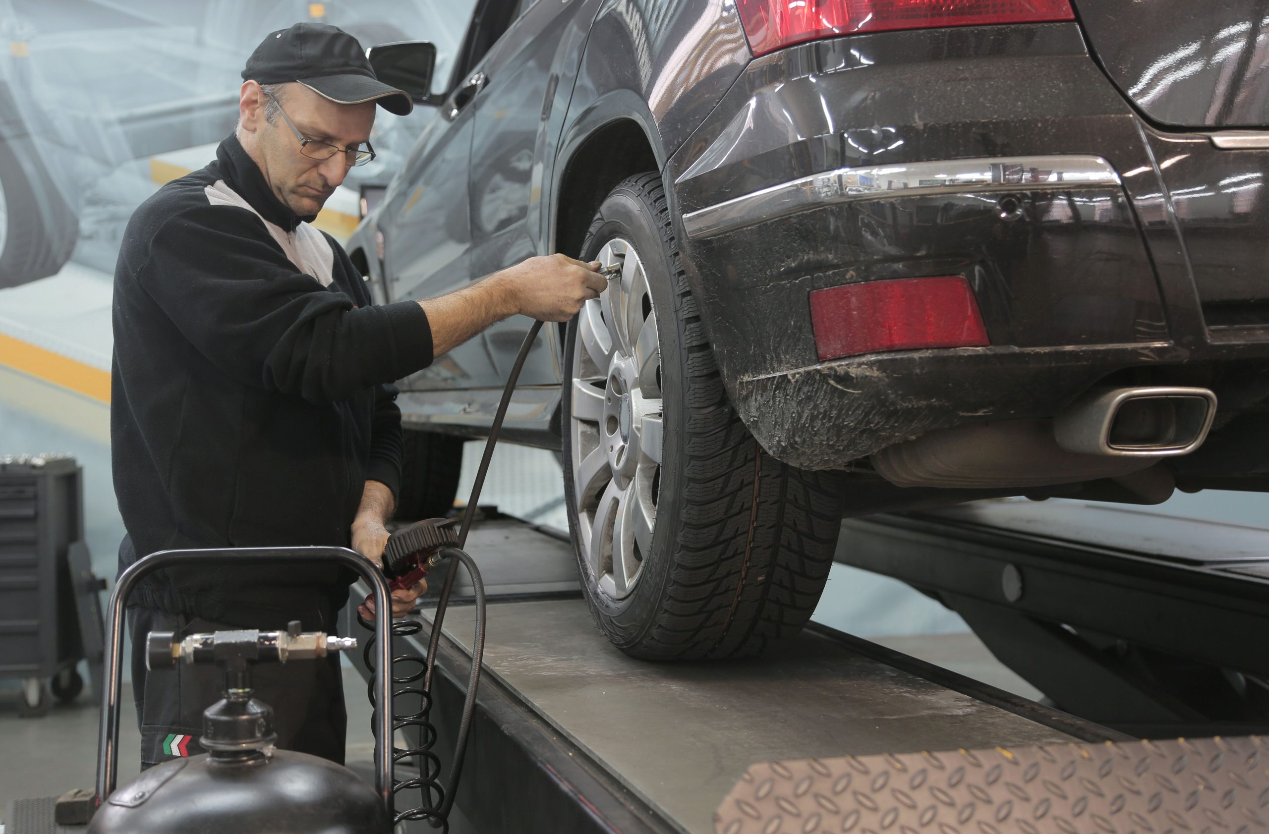 Mecanicien qui gonfle un pneu de voiture en atelier