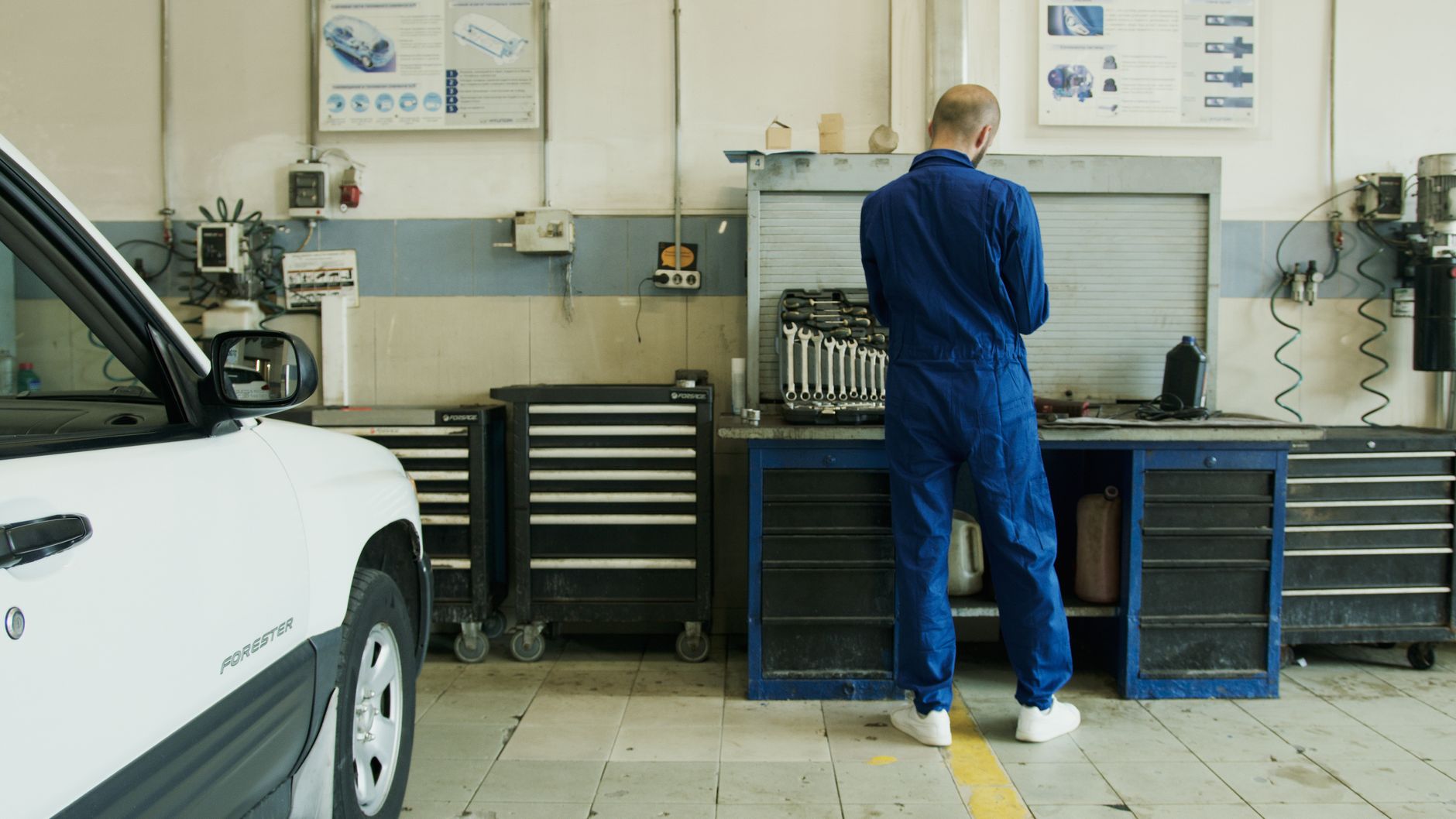 Mécanicien au travail dans un garage devant un véhicule ouvert