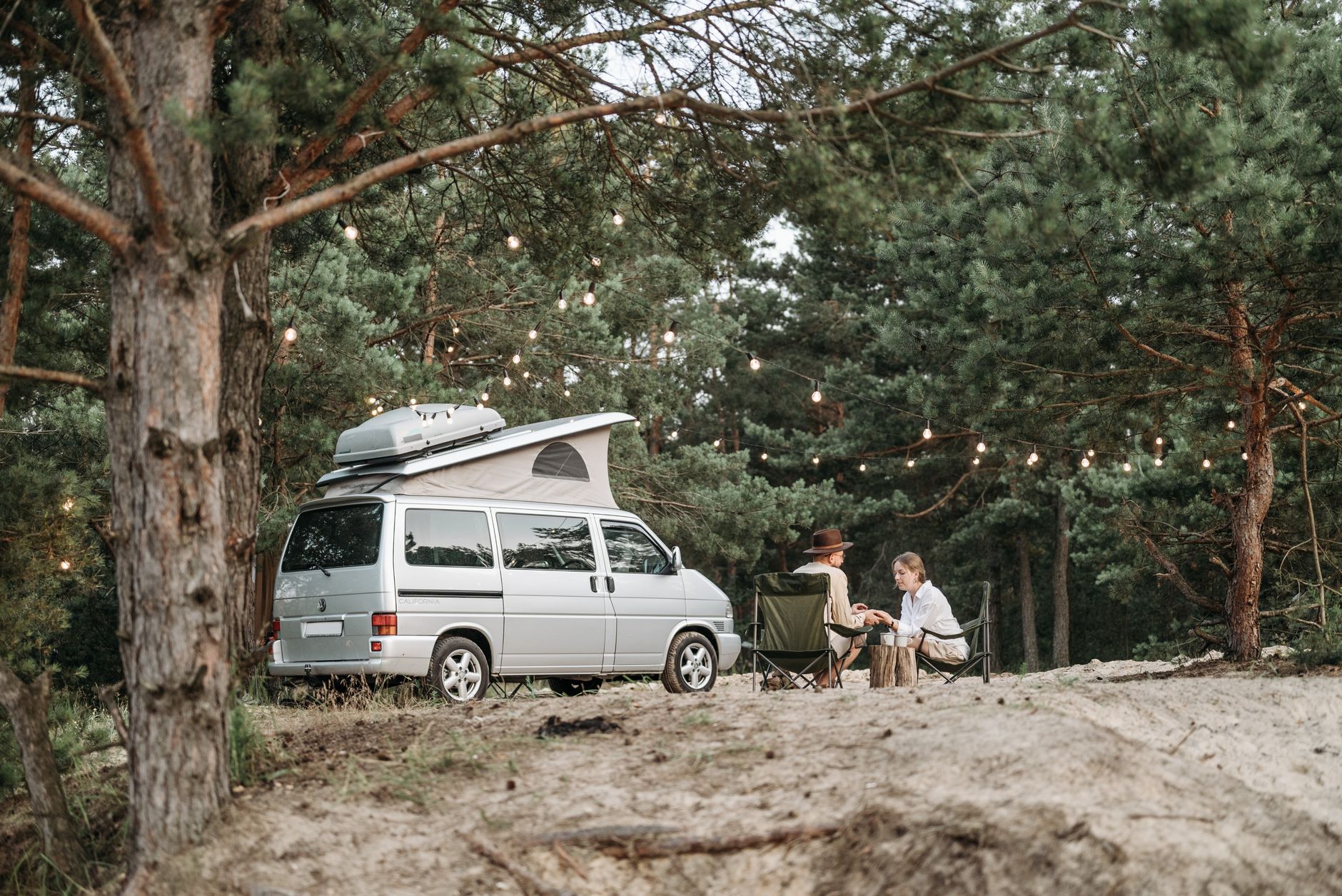 Van aménagé de type California garé en camping sous les pins