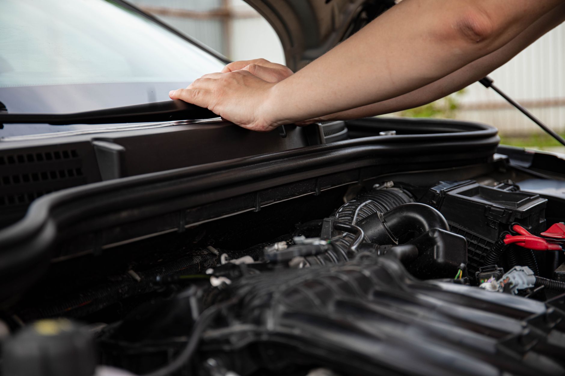 Mains qui manipulent une pièce sous le capot moteur