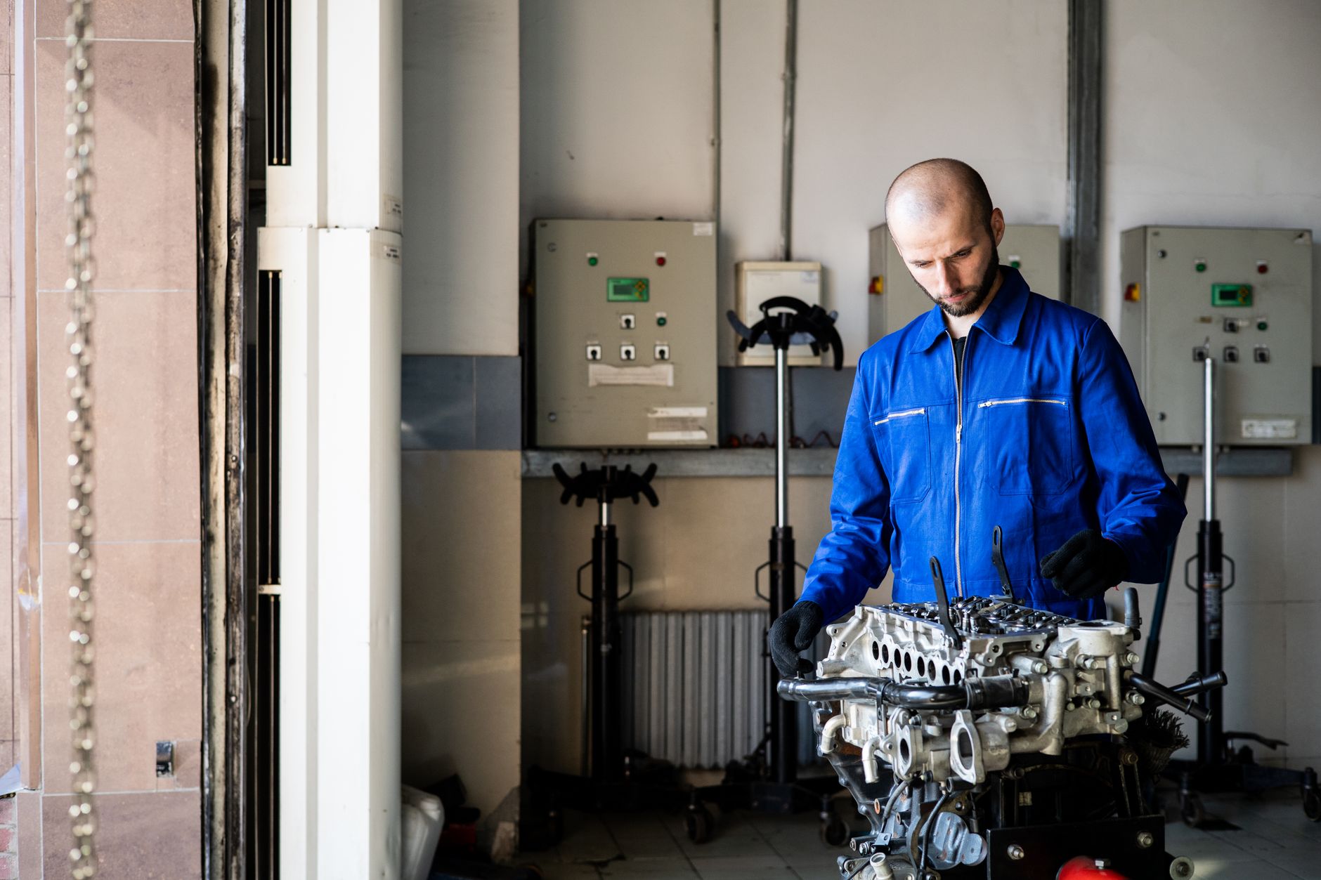 Mécanicien en combinaison bleue devant un moteur ouvert