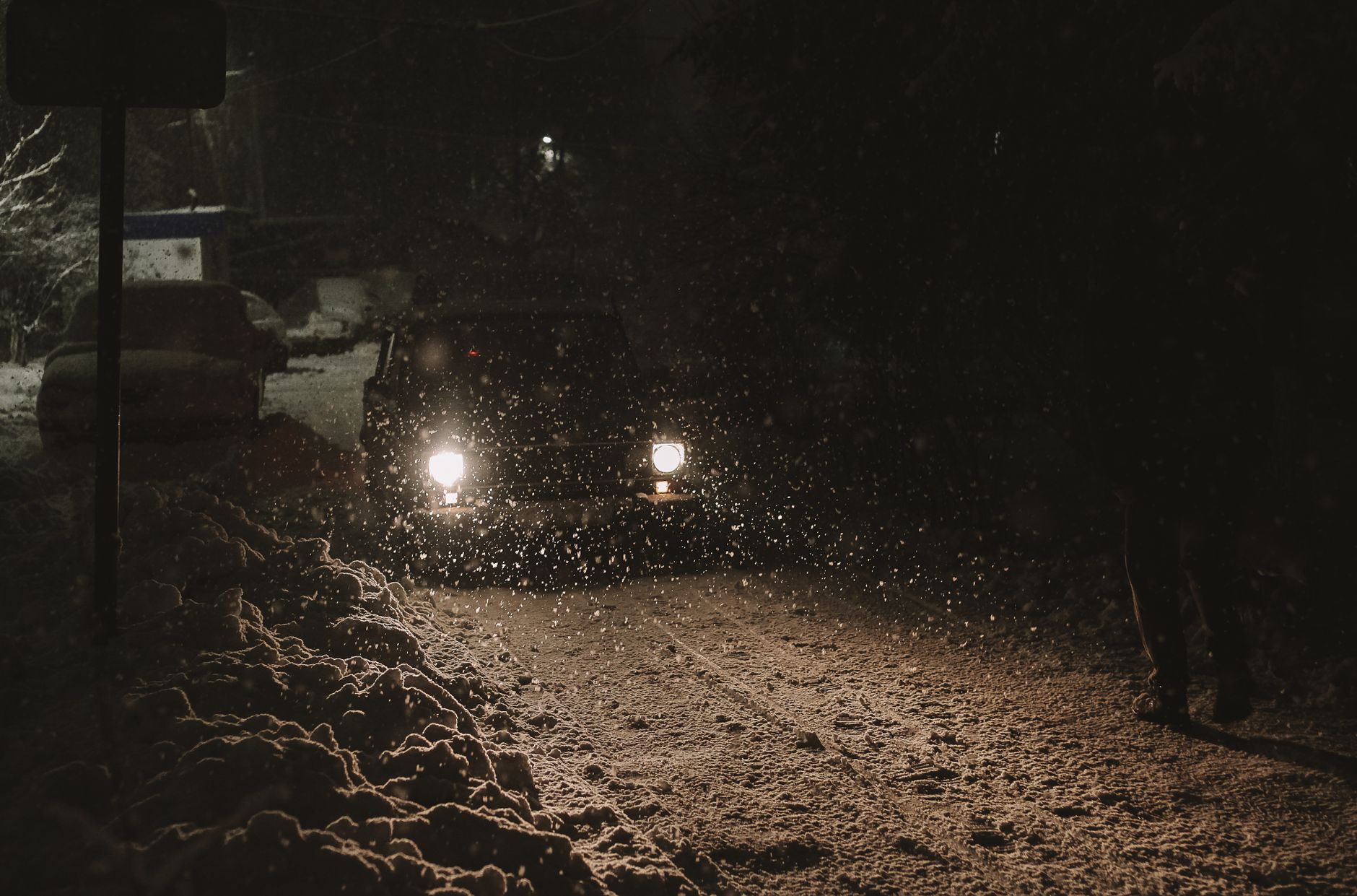 Voiture roulant de nuit sous la neige, phares allumés