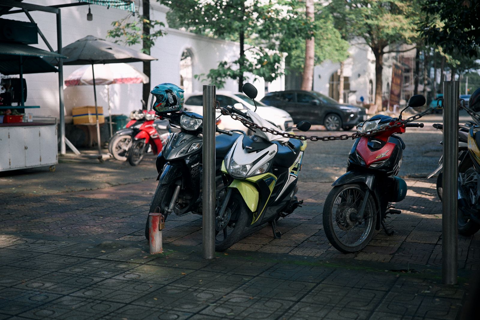 Trois motos antivolées par une chaîne sur un trottoir