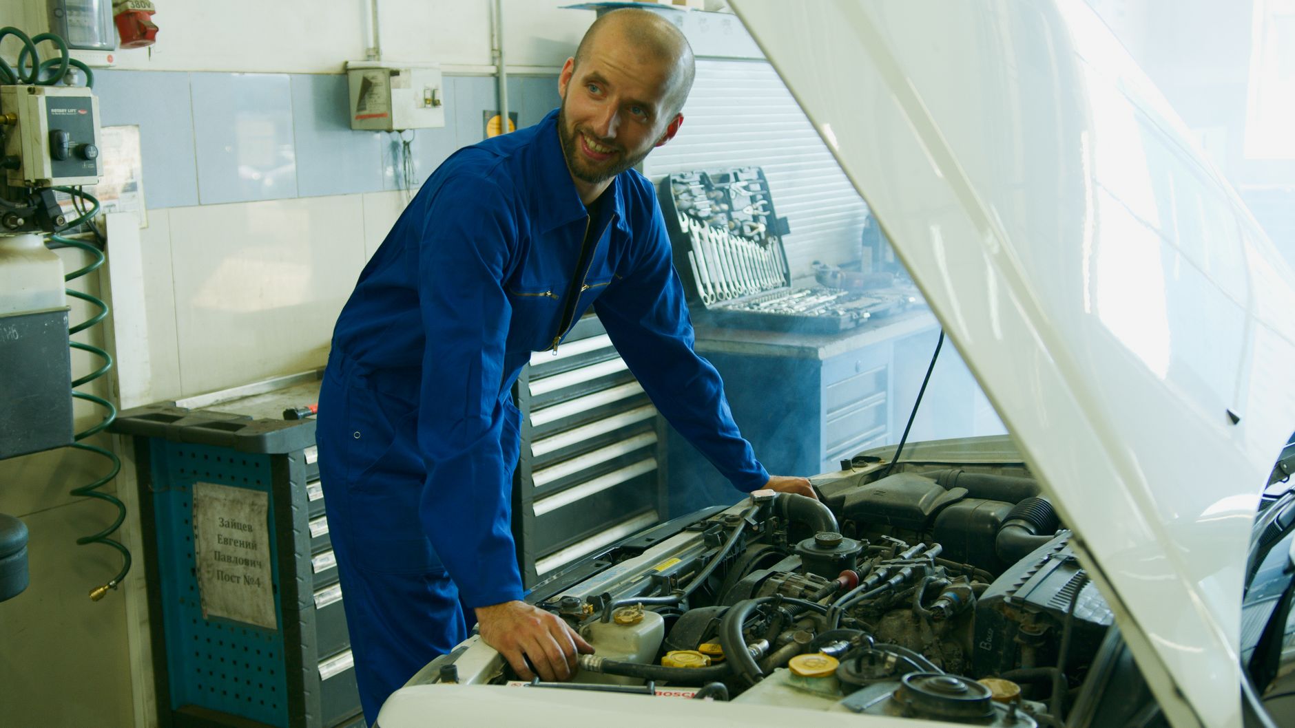 Mécanicien vérifiant le moteur d’une voiture au garage
