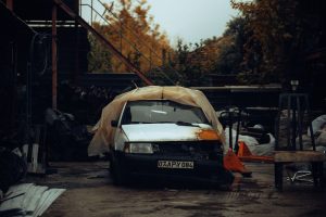 Voiture ancienne sous une bache dans une casse