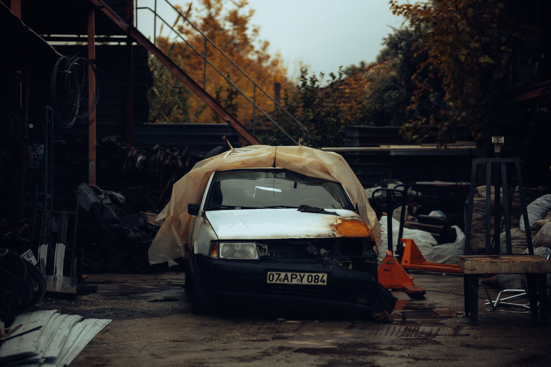 Voiture ancienne sous une bache dans une casse